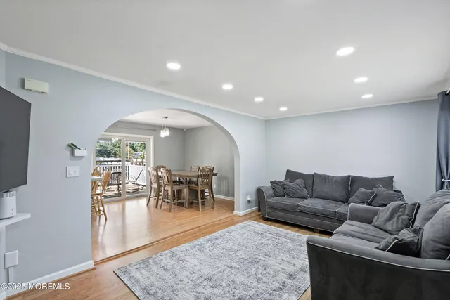 a living room with furniture and a dining table with wooden floor
