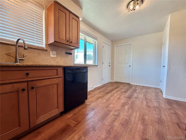 a kitchen with granite countertop wooden cabinets a sink and dishwasher
