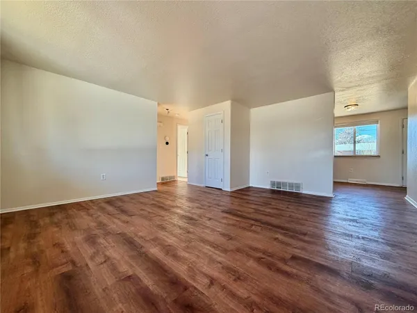 a view of an empty room with window and wooden floor