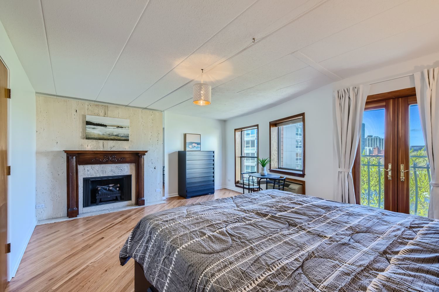 711 West Gordon Terrace, Unit 701 Chicago, IL 60613 - Photo 19 of 27 a bedroom with a large bed and a fireplace