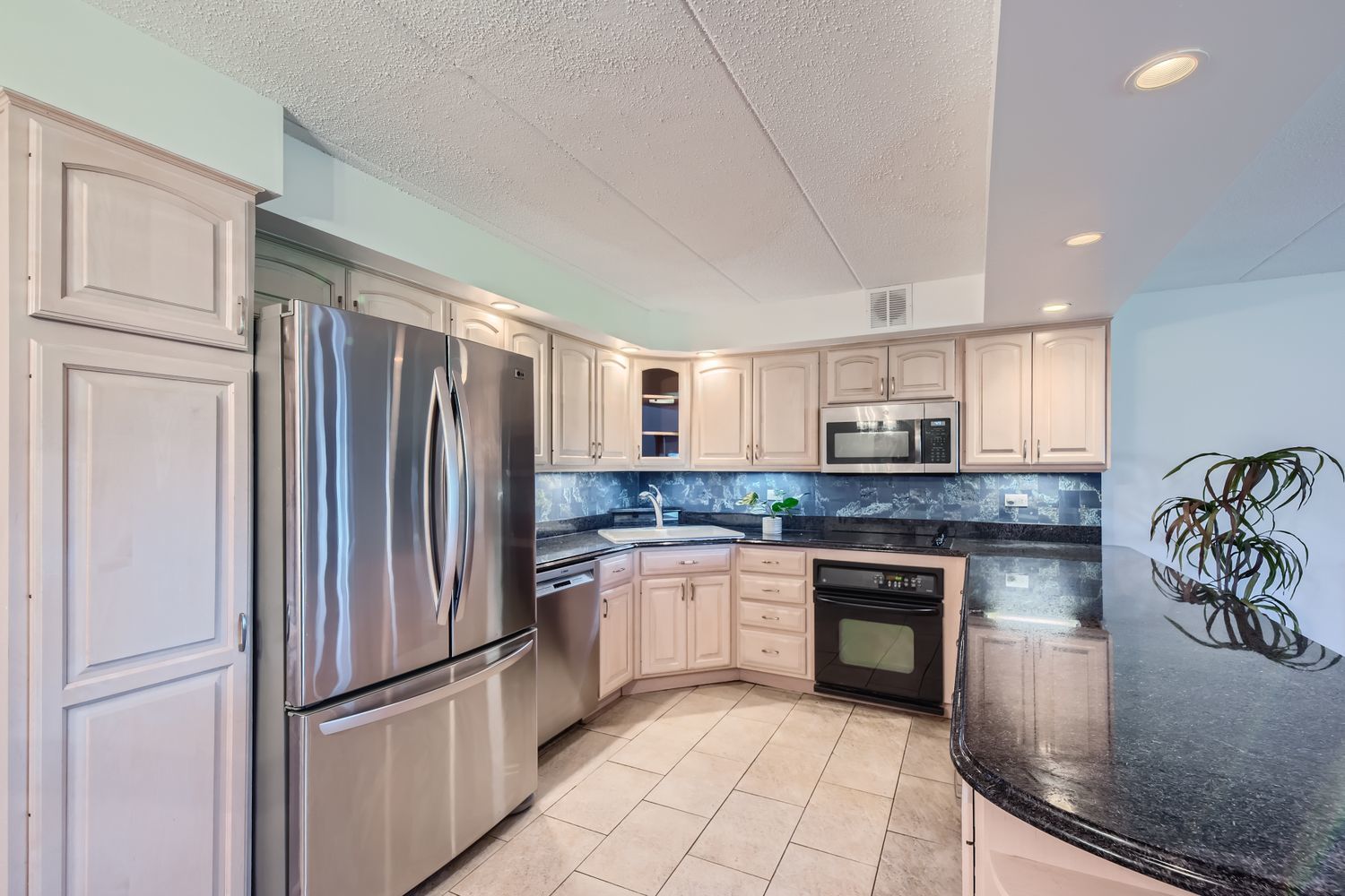 711 West Gordon Terrace, Unit 701 Chicago, IL 60613 - Photo 6 of 27 a kitchen with stainless steel appliances granite countertop a refrigerator a stove and a sink with wooden floor