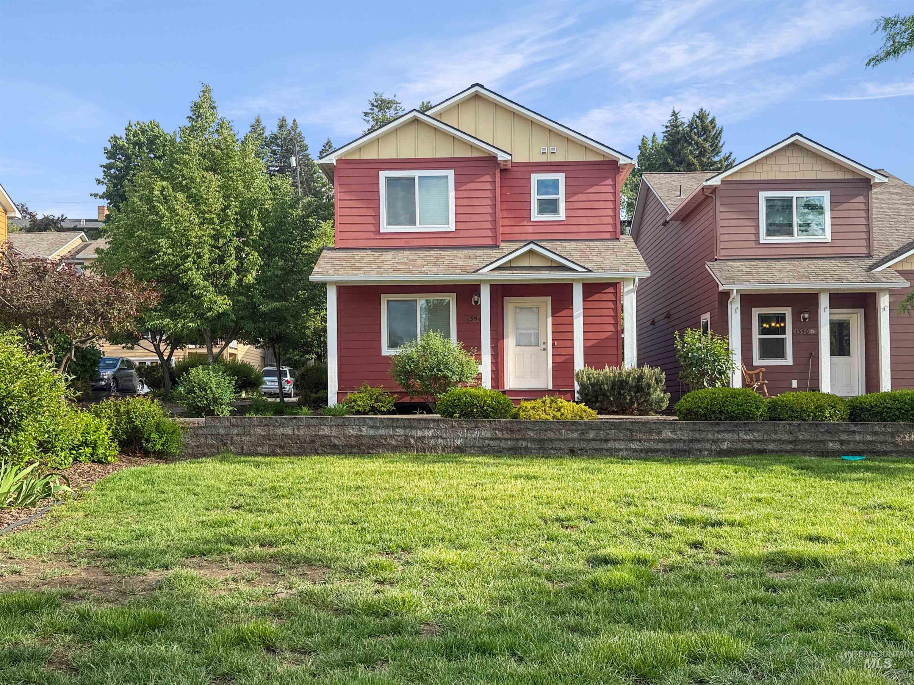 Two-story red siding residence featuring a covered front entry porch, white window trim, and contrasting yellow gables