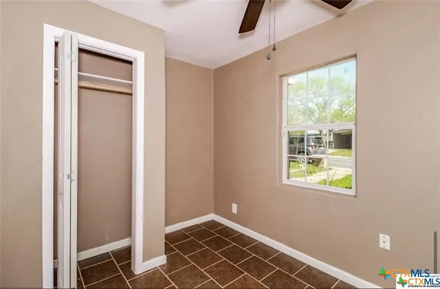 a view of an empty room with window and closet area