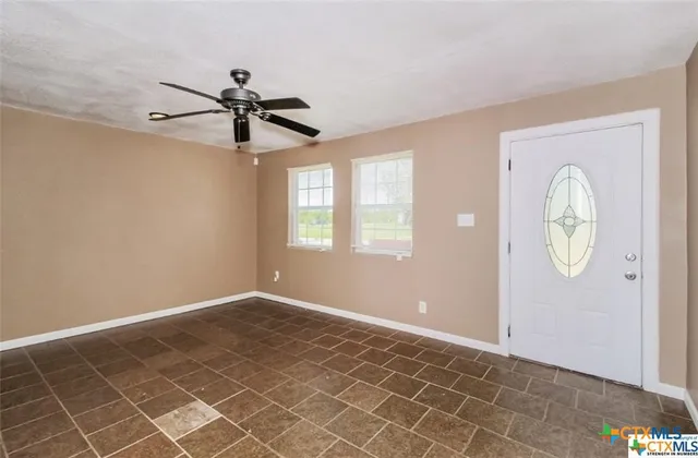 an empty room with windows and fan