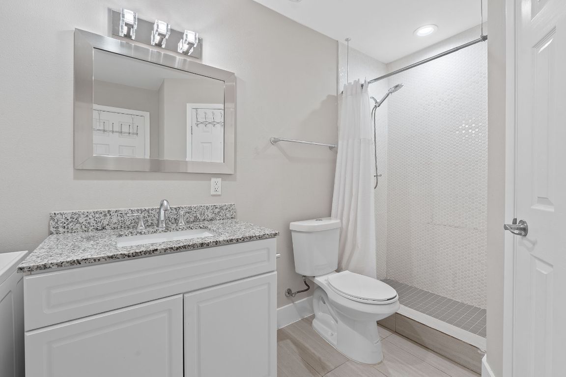 935 La Posada Drive, Unit 254 Austin, TX 78752 - Photo 11 of 19 Bathroom with vanity, a stall shower, washer / clothes dryer, and light wood-style floors