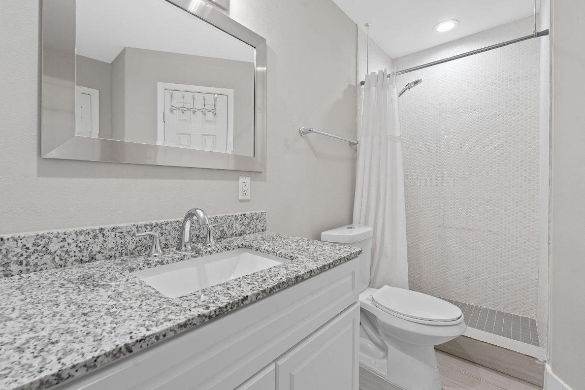 935 La Posada Drive, Unit 254 Austin, TX 78752 - Photo 13 of 19 Full bathroom with a stall shower, vanity, and light wood finished floors