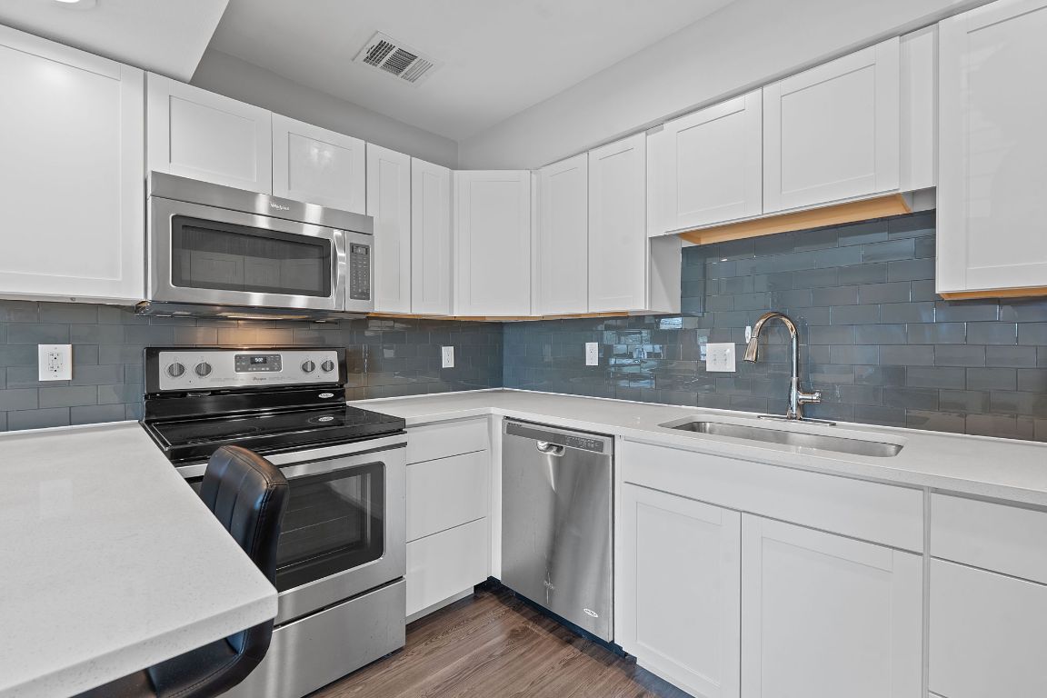 935 La Posada Drive, Unit 254 Austin, TX 78752 - Photo 3 of 19 Kitchen with white cabinetry, appliances with stainless steel finishes, and tasteful backsplash