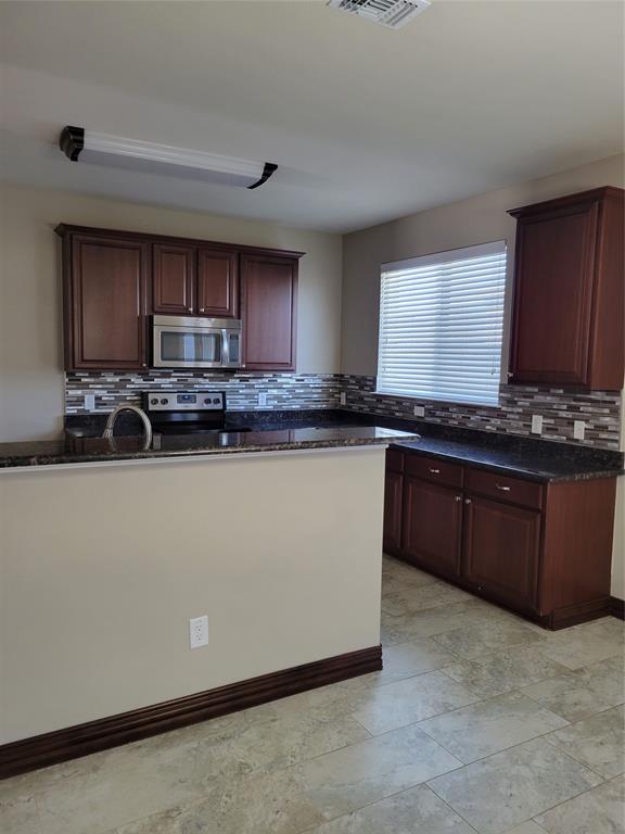 1633 Kawati Way Krum, TX 76249 - Photo 7 of 17 a kitchen with kitchen island granite countertop a sink a stove top oven a counter space and cabinets