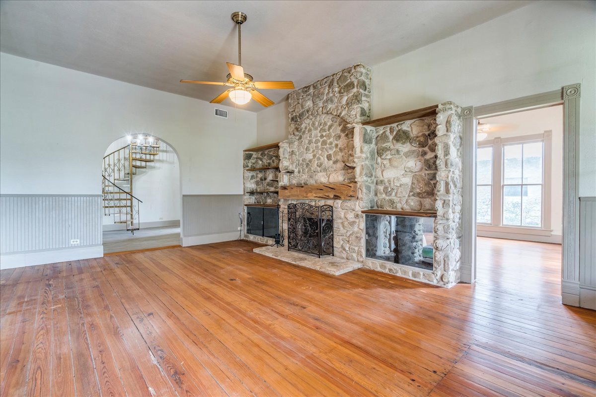 6400 Cypress Road Kyle, TX 78640 - Photo 14 of 33 Living area featuring wood-finish flooring, a stone fireplace with a wood mantle, and a brass ceiling fan