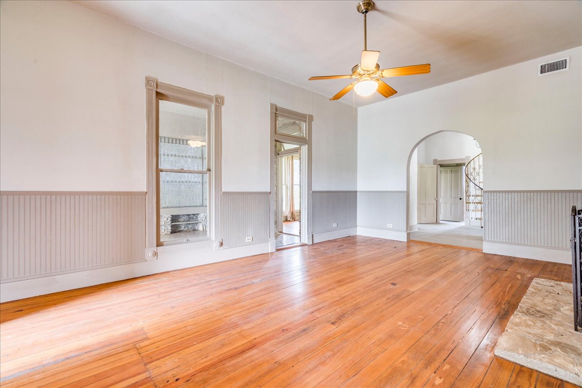 6400 Cypress Road Kyle, TX 78640 - Photo 15 of 33 Spacious room featuring wood-finish flooring, beadboard wainscoting, an arched doorway, and a ceiling fan with integrated lighting