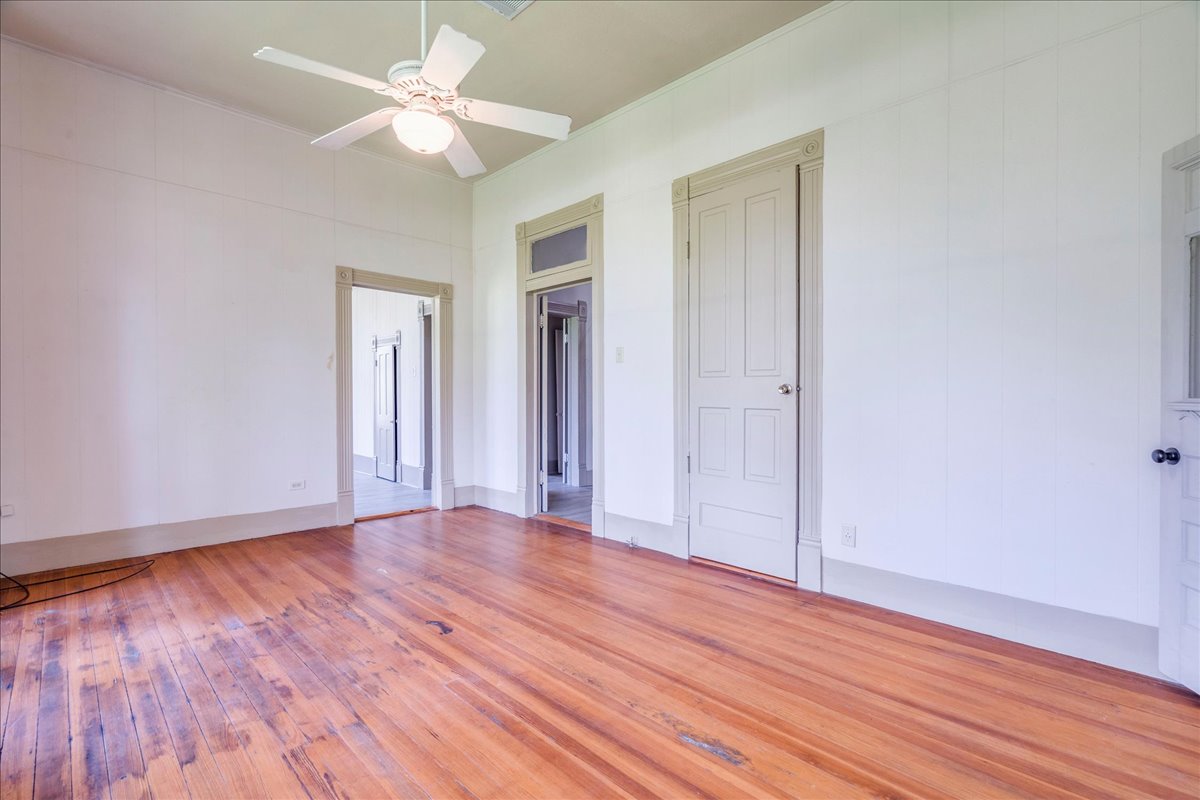 6400 Cypress Road Kyle, TX 78640 - Photo 19 of 33 Hardwood flooring throughout, featuring a ceiling fan with integrated lighting, multiple doorways, and paneled interior doors with substantial trim