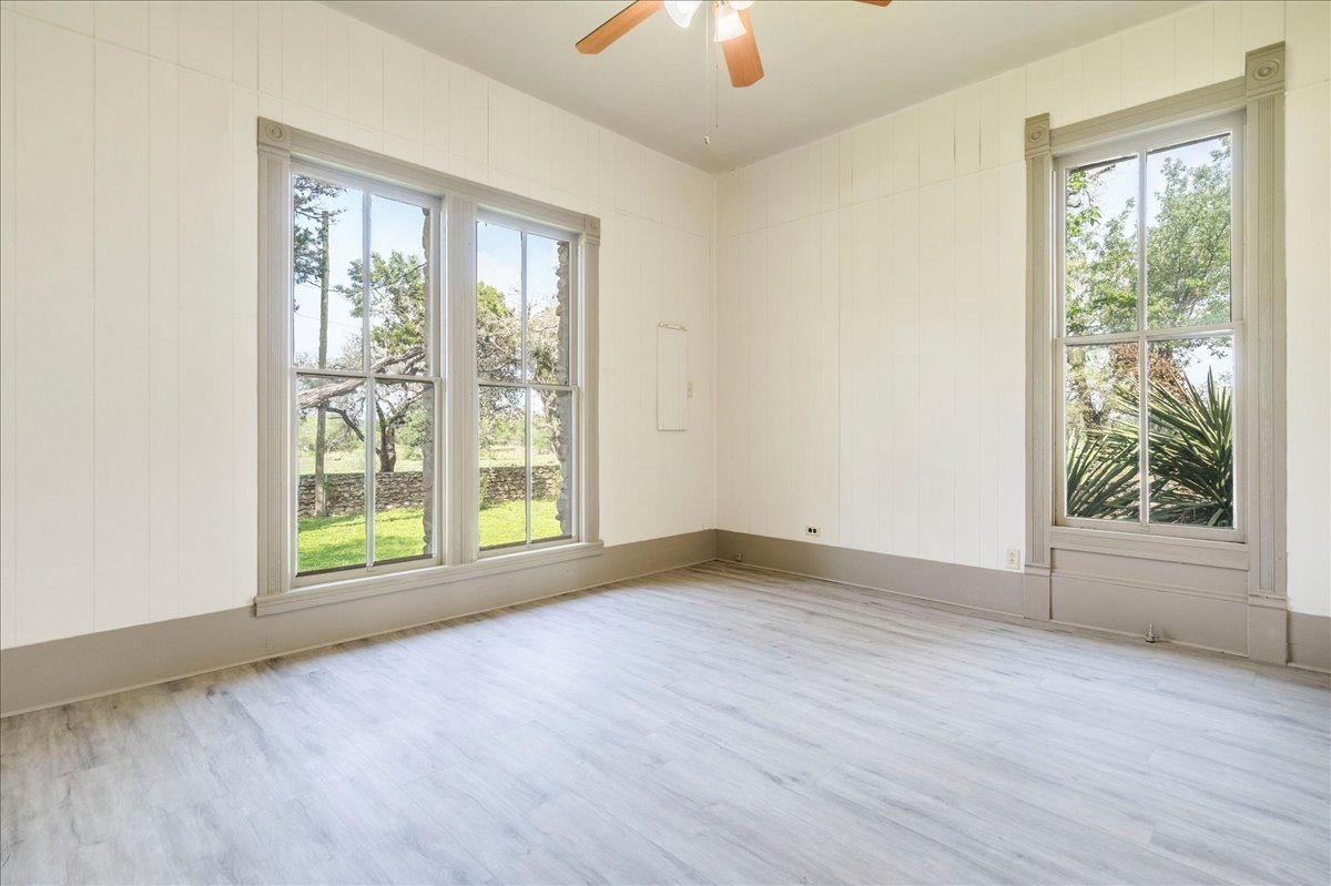 6400 Cypress Road Kyle, TX 78640 - Photo 20 of 33 Spacious room featuring light wood-finish flooring, two large windows with decorative trim, and board and batten wall details