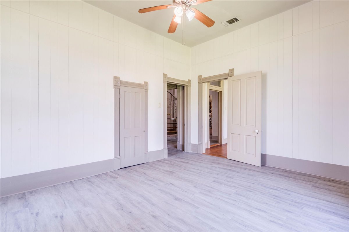 6400 Cypress Road Kyle, TX 78640 - Photo 21 of 33 Spacious interior room featuring light wood-finish flooring, white vertical plank walls, and a ceiling fan with light fixture