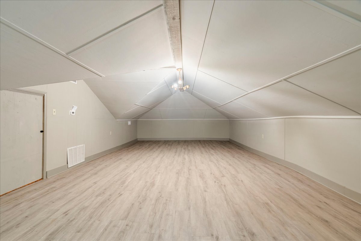 6400 Cypress Road Kyle, TX 78640 - Photo 26 of 33 Spacious attic room featuring wood-finish flooring, a neutral color palette, sloped ceilings, and a central lighting fixture
