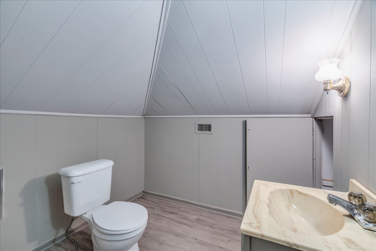 6400 Cypress Road Kyle, TX 78640 - Photo 28 of 33 Bathroom with angled paneled ceiling, light gray wainscoting, wood-finish flooring, and vanity with integrated sink