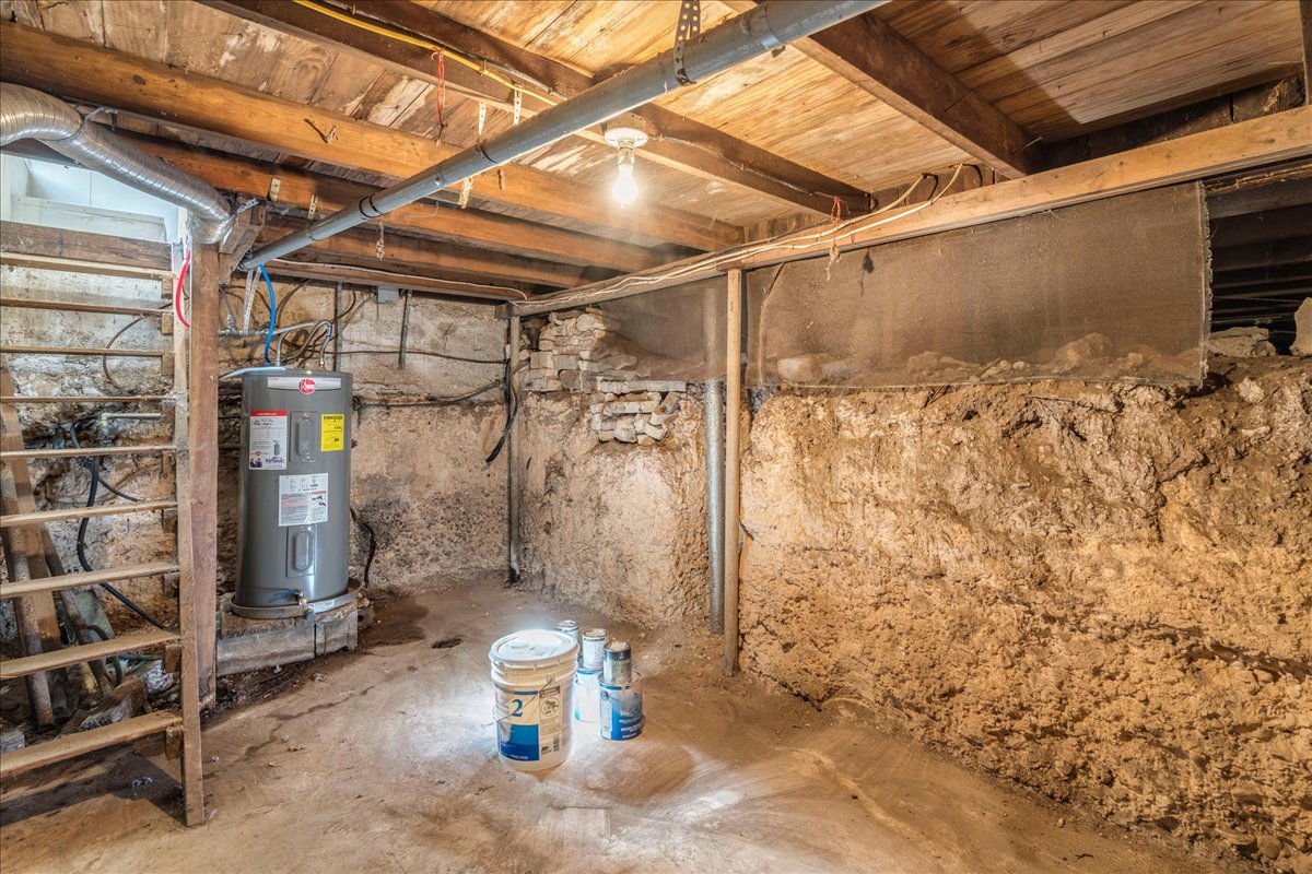 6400 Cypress Road Kyle, TX 78640 - Photo 30 of 33 Basement area featuring a water heater, visible wooden floor joists, concrete flooring, and exposed utility piping