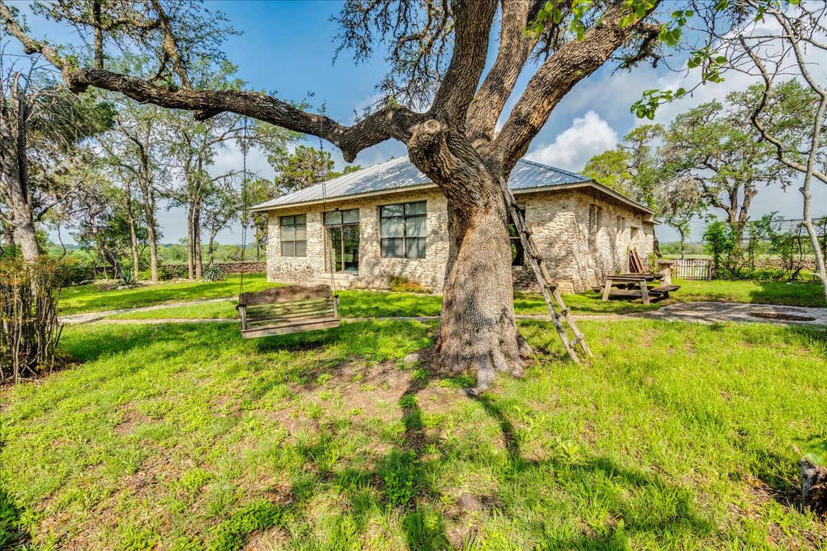 6400 Cypress Road Kyle, TX 78640 - Photo 3 of 33 Stone facade residence featuring a metal roof, multiple windows, and a large tree with a swing