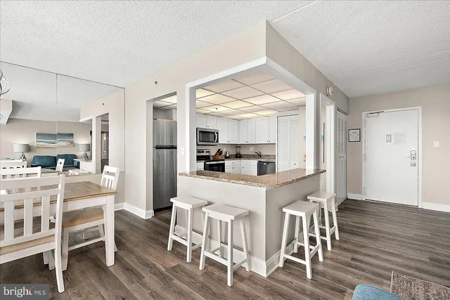 a kitchen with stainless steel appliances kitchen island granite countertop a table chairs and a refrigerator