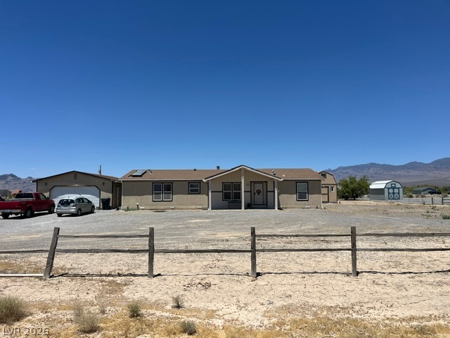 350 East Stagecoach Road Pahrump, NV 89060 - Photo 2 of 4 A spacious desert homestead features a wide front entry, an attached garage, and a distant barn against a mountain backdrop.