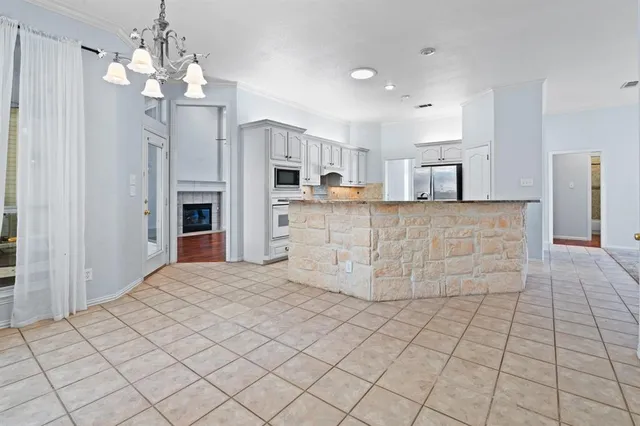 a large white kitchen with kitchen island granite countertop a stove a sink a window and white cabinets