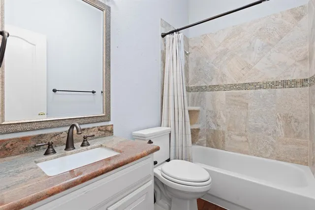 a bathroom with a granite countertop sink mirror vanity and toilet