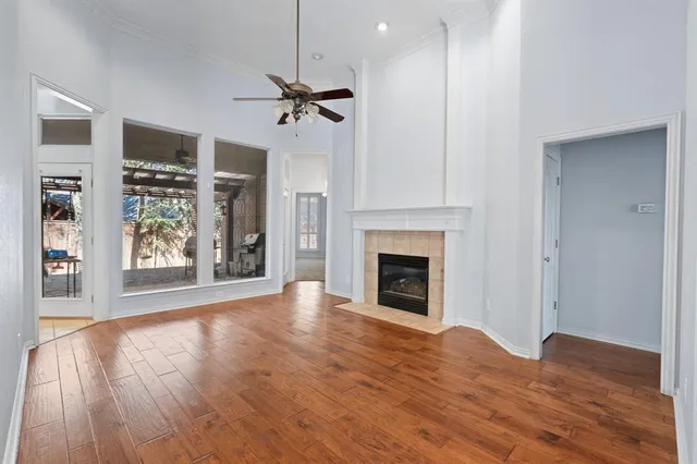 a view of an empty room with wooden floor fireplace and a window