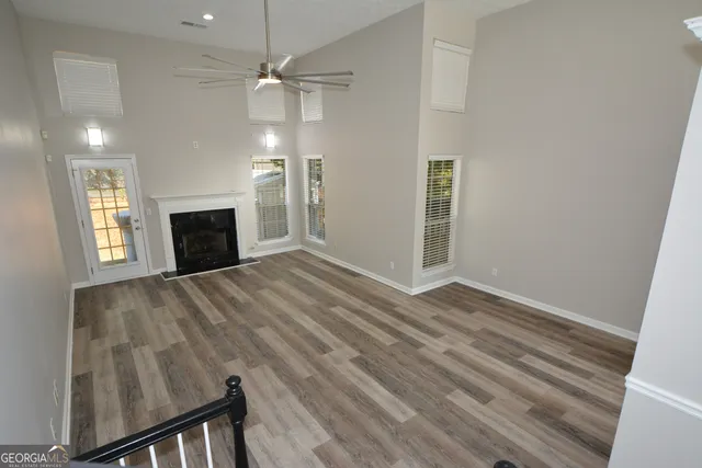 an empty room with wooden floor fireplace and windows
