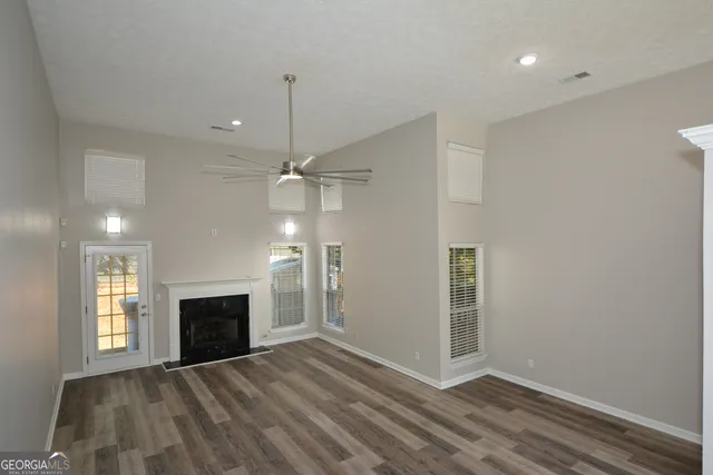 an empty room with wooden floor fireplace and windows