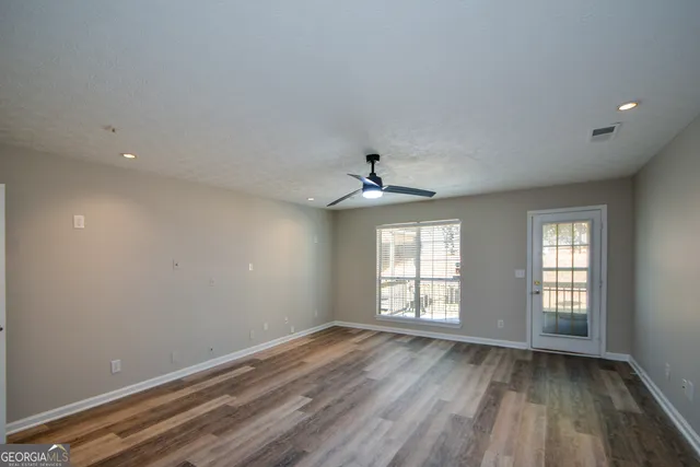 an empty room with wooden floor and windows