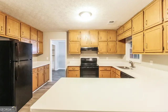 a large kitchen with stainless steel appliances granite countertop a refrigerator a stove and a sink dishwasher
