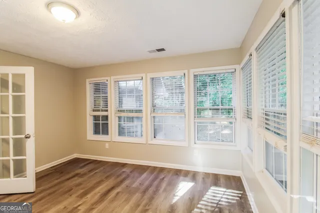a view of an empty room with wooden floor and a window