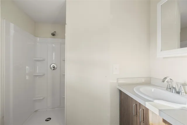 a bathroom with a granite countertop sink a shower and a mirror