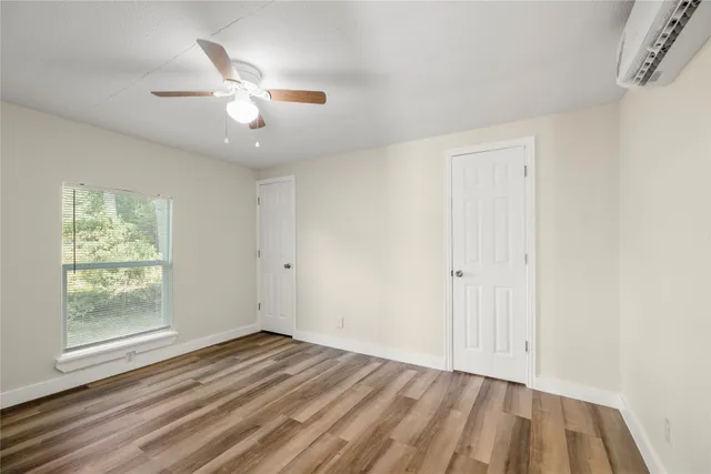 an empty room with wooden floor fan and windows