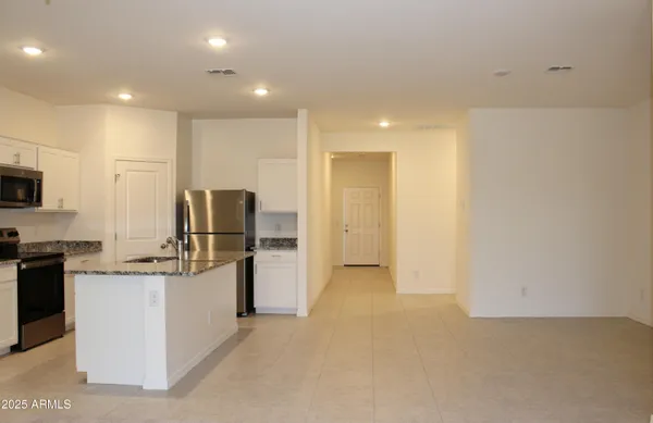 a view of a kitchen with refrigerator and white cabinets