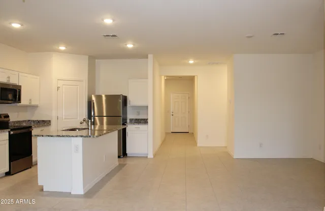 a view of a kitchen with refrigerator and white cabinets