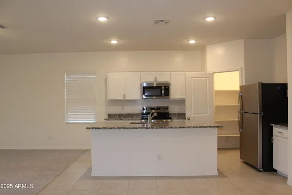 a large kitchen with stainless steel appliances a sink a counter and a refrigerator