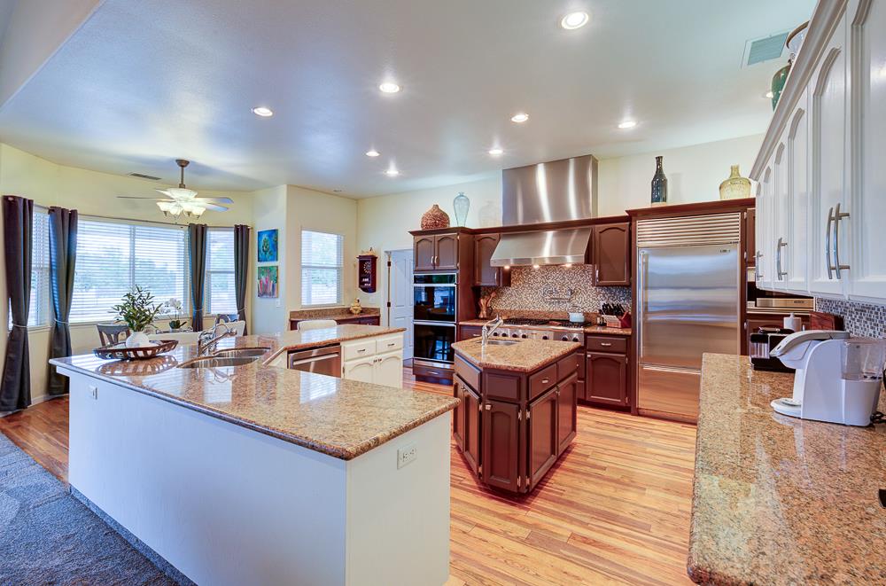 17465 Monreal Road Madera, CA 93636 - Photo 23 of 59 a kitchen with stainless steel appliances granite countertop a stove top oven a refrigerator and kitchen island