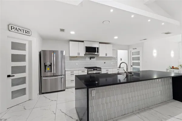 a kitchen with stainless steel appliances granite countertop a refrigerator and a sink