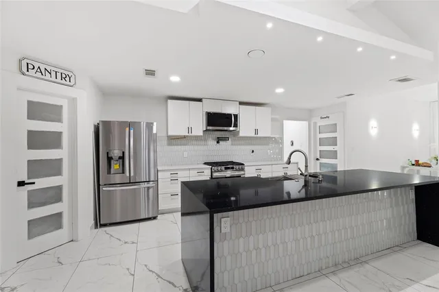 a kitchen with stainless steel appliances granite countertop a refrigerator and a sink