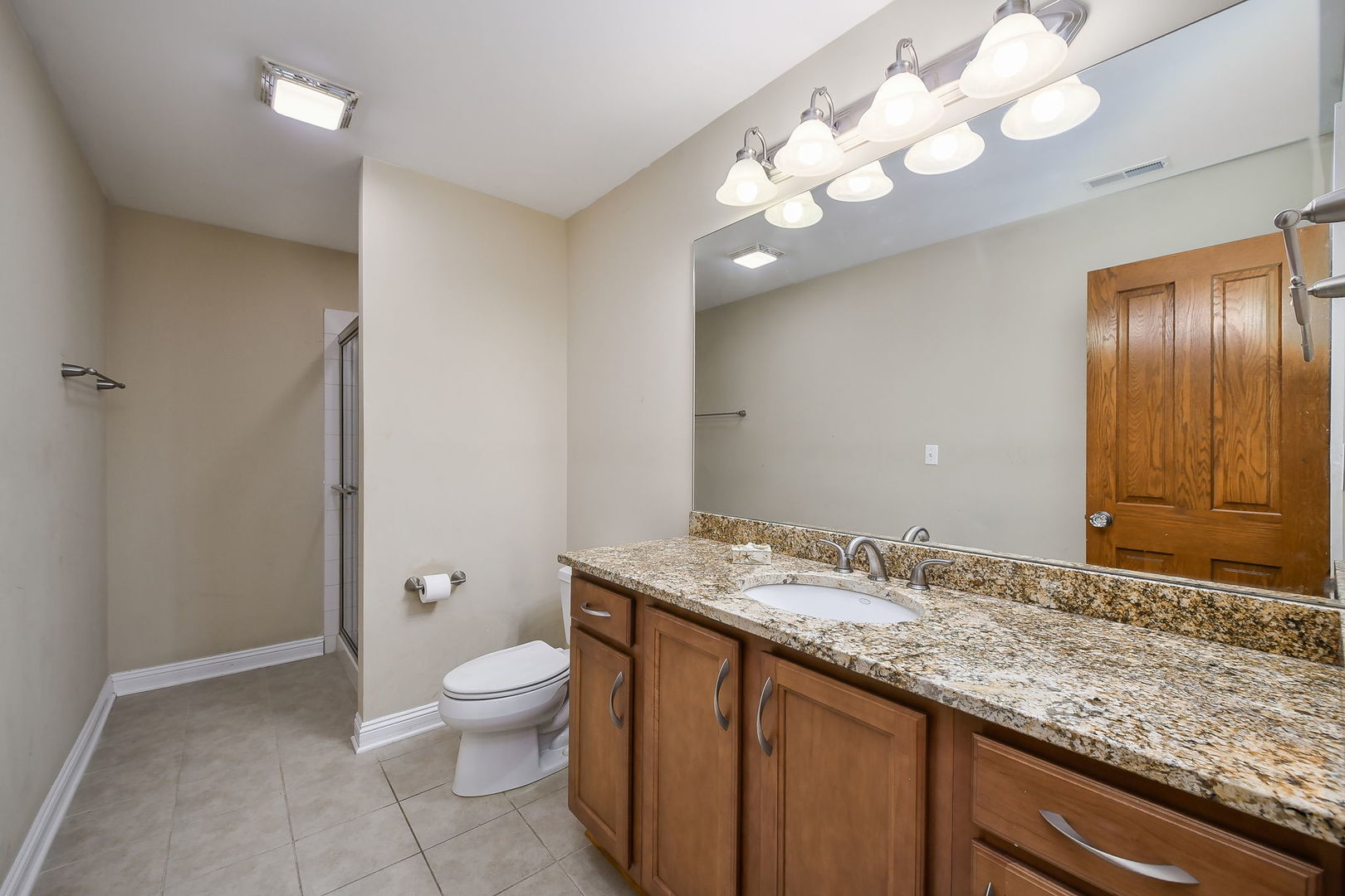 821 Wellner Road Naperville, IL 60540 - Photo 37 of 56 a bathroom with a granite countertop sink a toilet and a large mirror