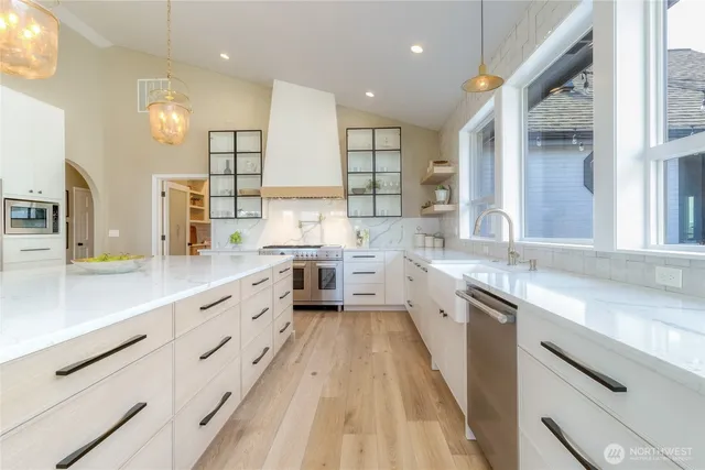 a large kitchen with stainless steel appliances sink a stove and cabinets