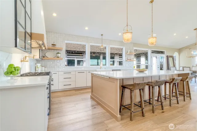 a kitchen with stainless steel appliances granite countertop a stove a sink a oven a dining table and chairs with wooden floor