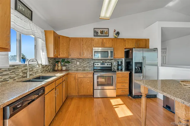a large kitchen with stainless steel appliances granite countertop a stove a sink and a refrigerator