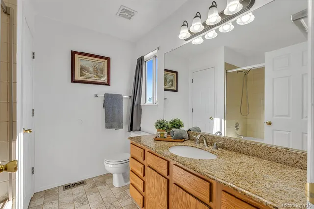 a bathroom with a granite countertop sink a toilet and a mirror