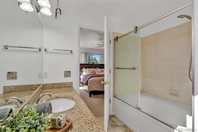 a bathroom with a granite countertop sink a mirror and shower
