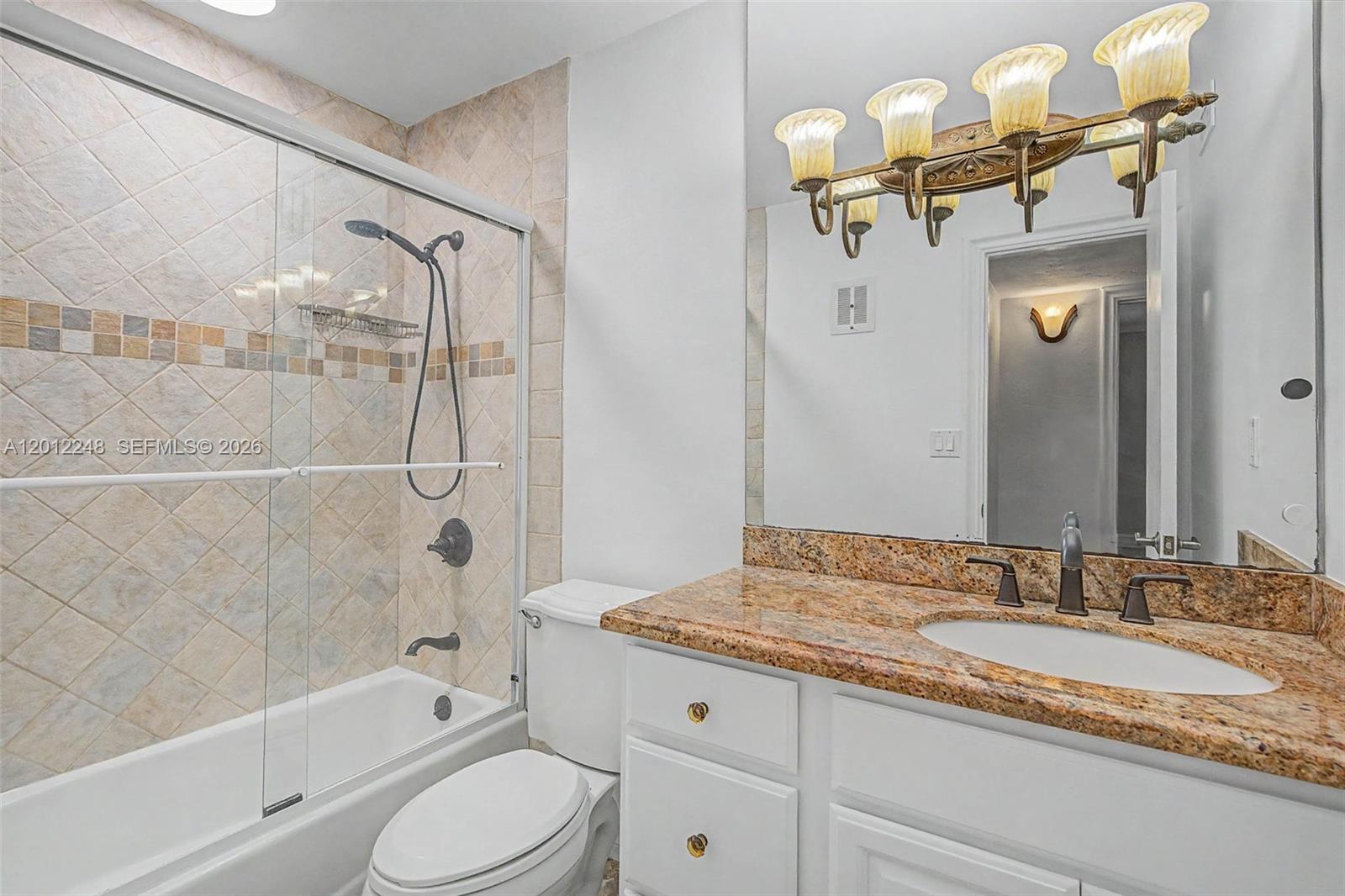 8609 Southwest 68th Court, Unit 22 Pinecrest, FL 33156 - Photo 6 of 15 a bathroom with a granite countertop sink a toilet and bathtub