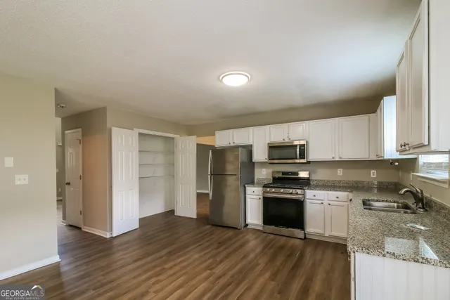 a kitchen with granite countertop a refrigerator and a stove top oven