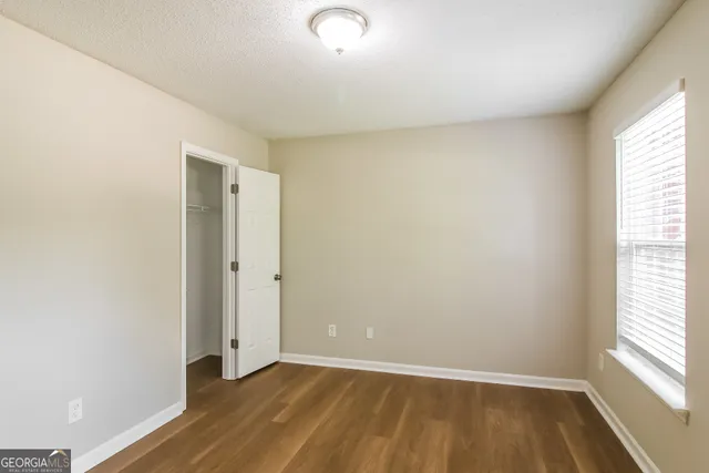 an empty room with wooden floor and windows
