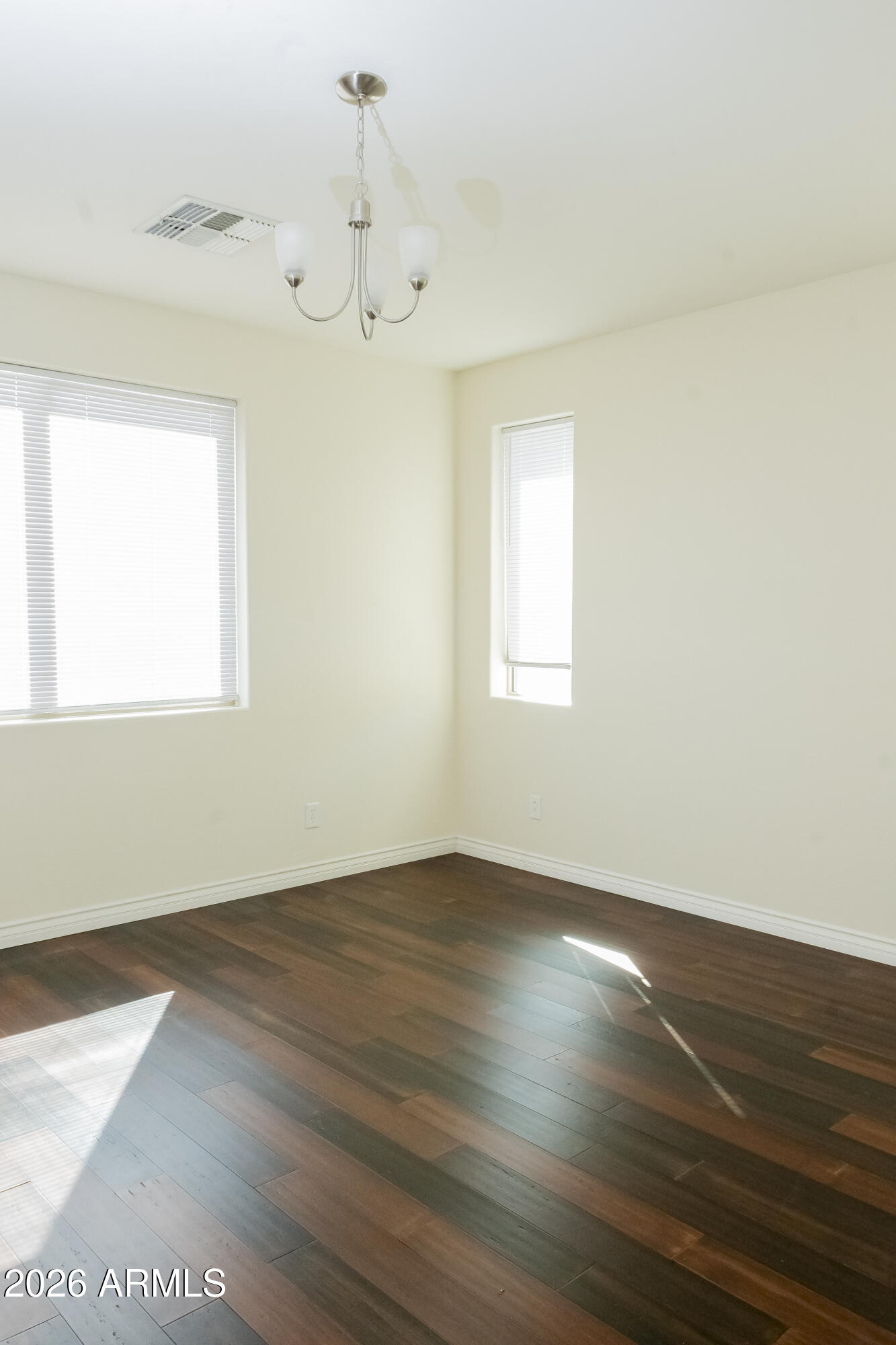 16045 West Almeria Road Goodyear, AZ 85395 - Photo 17 of 31 an empty room with wooden floor and windows
