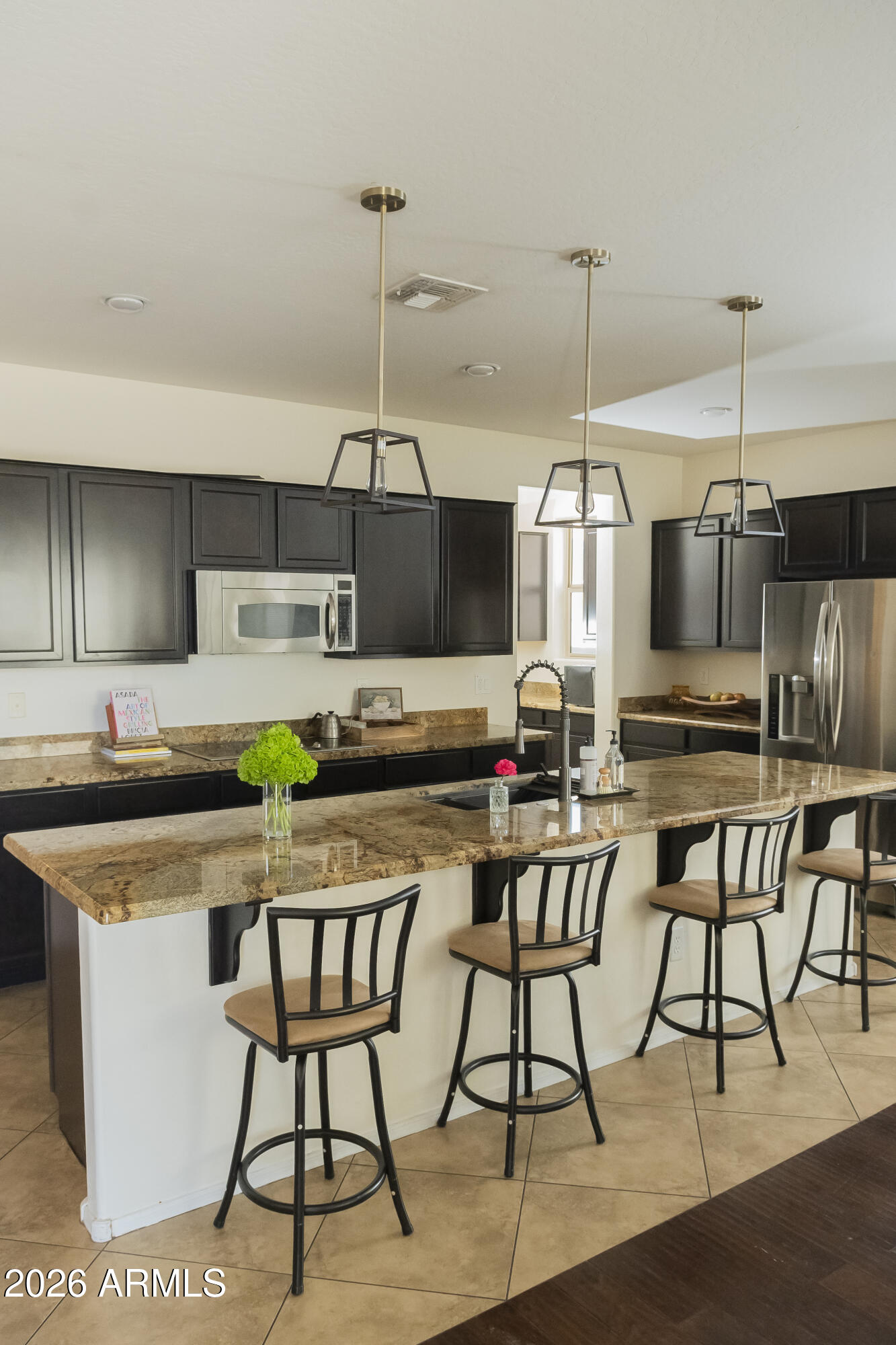 16045 West Almeria Road Goodyear, AZ 85395 - Photo 9 of 31 a kitchen with stainless steel appliances a dining table chairs and white cabinets